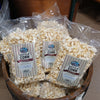 Clear plastic bags filled with handcrafted kettle corn featuring striped labels, arranged in a rustic wooden bowl, a sweet nostalgic snack from USA made and Kitchen & Food collections.