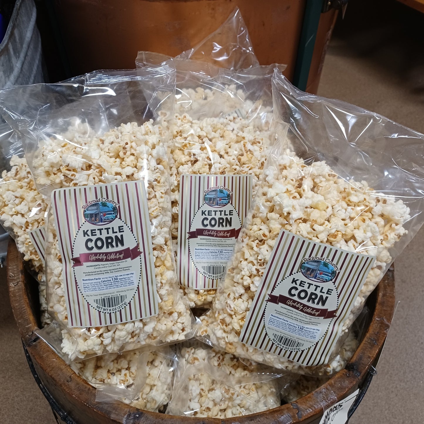 Clear plastic bags filled with handcrafted kettle corn featuring striped labels, arranged in a rustic wooden bowl, a sweet nostalgic snack from USA made and Kitchen & Food collections.