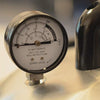 Close-up of a geared pressure gauge marked with temperature and pressure readings, warning not to operate before reading instructions, featured in Food Preservation, Canning, USA Made, and Kitchen & Food collections.
