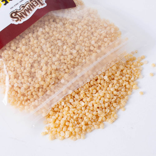 Clear resealable bag spilling small natural beeswax pellets, ideal for handcrafted candle making, featured in lamps and lighting, candlemaking supplies, and best sellers collections.