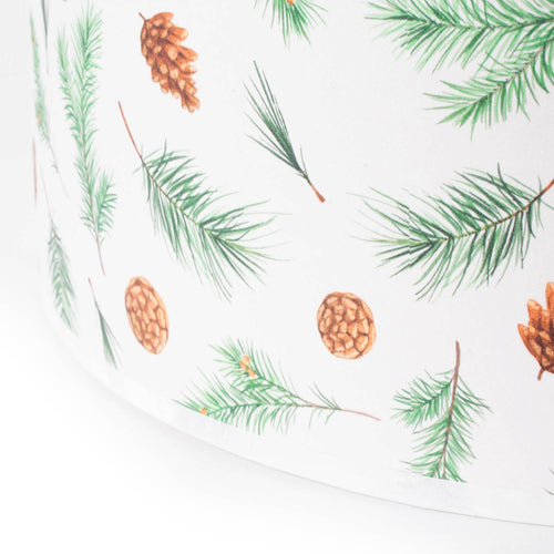 Close-up of a parchment lamp shade with delicate pine bough and pine cone prints, designed for a soft, festive glow; featured in Lamps & Lighting and Lamp Shades collections.
