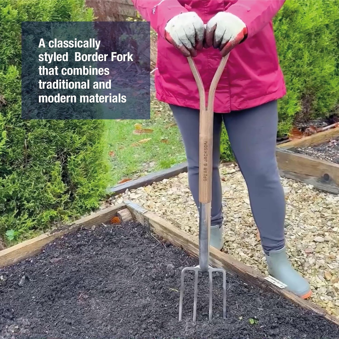 Person wearing gloves and pink jacket holding a traditional-style border fork with a stainless steel head and wooden handle, positioned over garden soil, suitable for Farm, Garden & Tool, Digging and Cultivating, Garden Accessories, Lawncare, Best Sellers, and Promo Eligible collections.