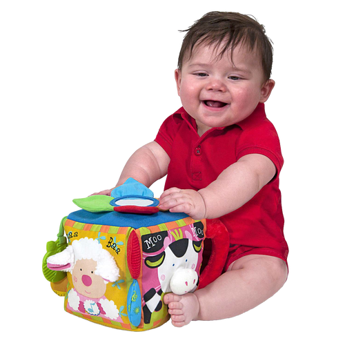 Baby in red outfit playing with colorful fabric musical farmyard cube featuring animal faces, textured details, and interactive sound elements, ideal for indoor play and learning.