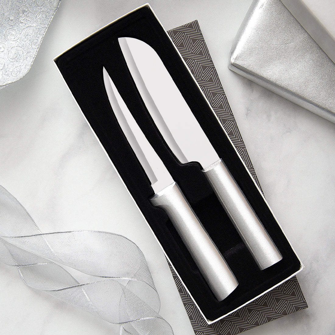 Two handcrafted stainless steel knives with smooth metallic handles in a black foam insert inside an elegant gift box, ideal for kitchen and food prep collections including Farm, Garden & Tool and USA Made.
