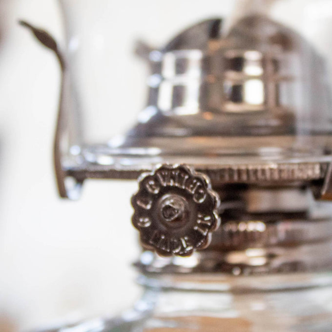 Close-up of a handcrafted metal adjustment knob on a clear glass oil lamp, part of lamps & lighting, oil lamps, table lamps, best sellers, and promo eligible collections.