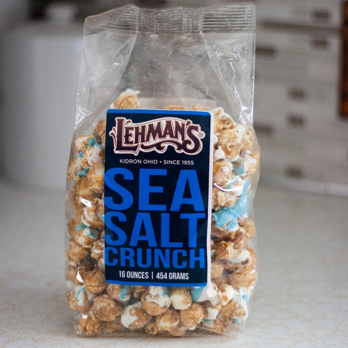 Clear bag of handcrafted caramel popcorn with sea salt crunch flavor and blue mix-ins, a unique sweet and savory snack made in USA, ideal for Kitchen & Food, Snacks and Sweets, Popcorn, USA Made, Best Sellers, and Promo Eligible collections.