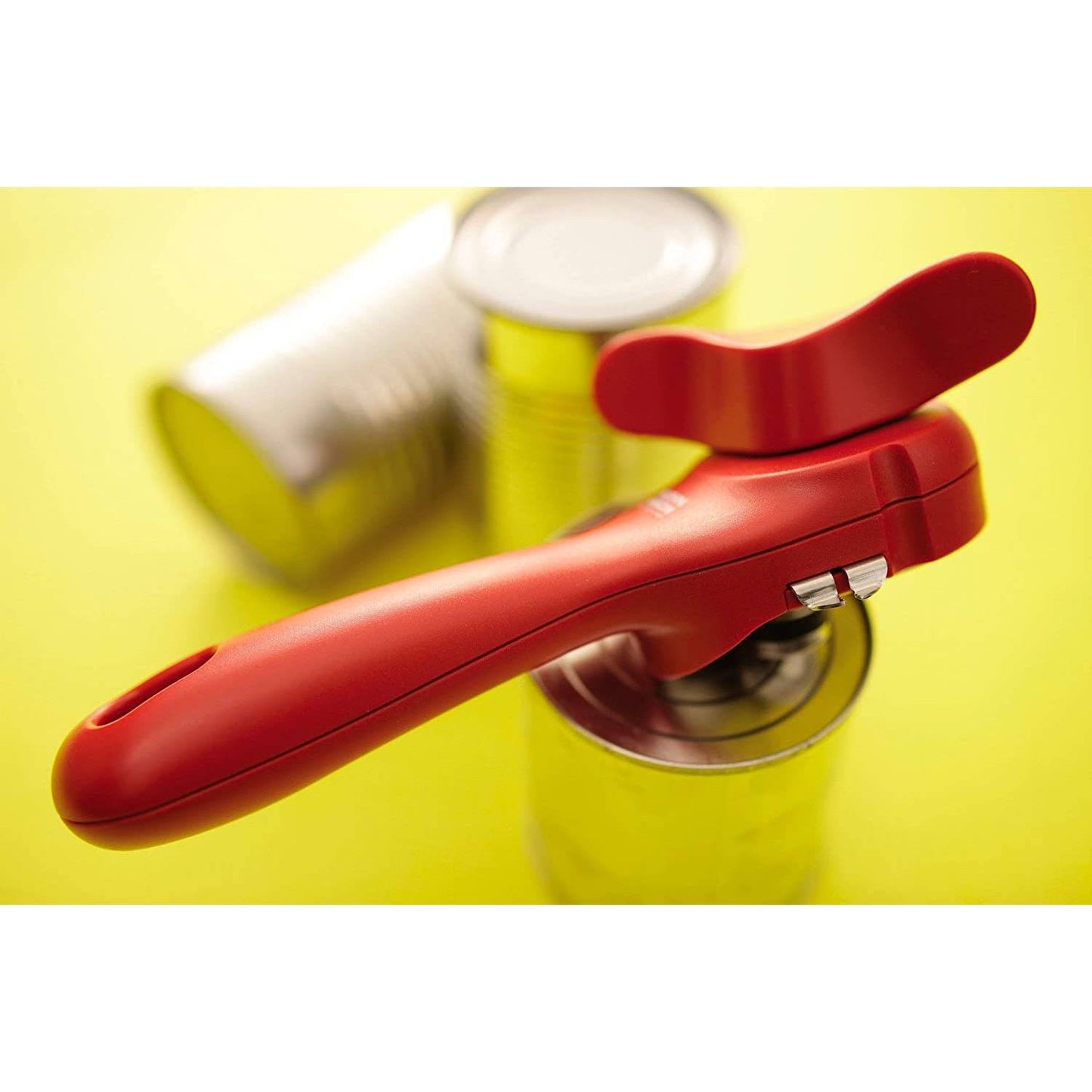 Red kitchen gadget can opener designed for safety with ergonomic handle, shown on a can against a yellow background, ideal for Kitchen Gadgets and Kitchen Accessories collections.