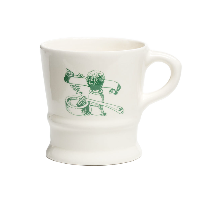 White porcelain shaving mug with vintage-style green illustration of shaving brush, soap, and straight razor, featured in Health & Wellness, Grooming and Personal Hygiene collections.