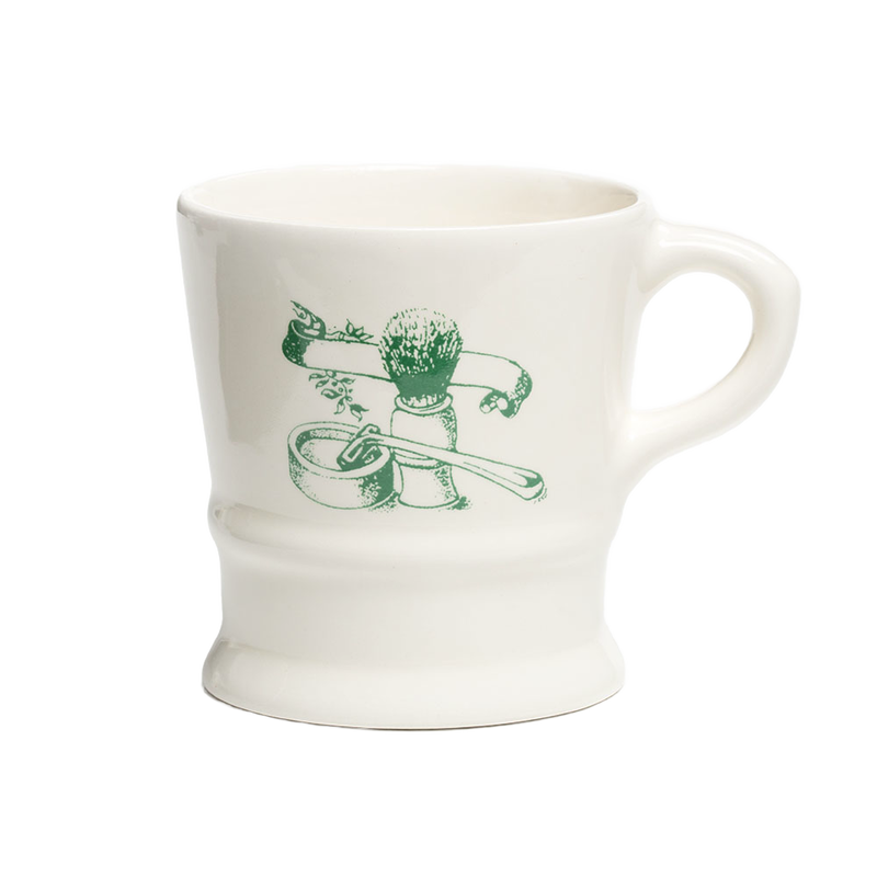White porcelain shaving mug with vintage-style green illustration of shaving brush, soap, and straight razor, featured in Health & Wellness, Grooming and Personal Hygiene collections.