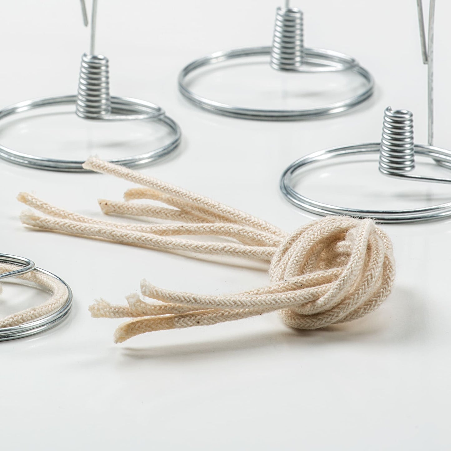 Braided cotton round wicks bundled together, surrounded by metal wick holders, handcrafted in USA, suitable for lamps and lighting, oil lamps, olive oil lamps, and parts and accessories collections.