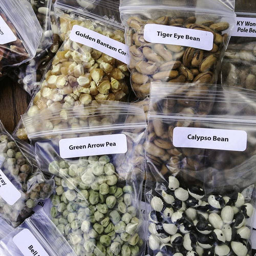Close-up of assorted heirloom seed packets including Golden Bantam Corn, Tiger Eye Bean, Green Arrow Pea, and Calypso Bean, featuring organic varieties for farm and garden use, USA made and promo eligible.