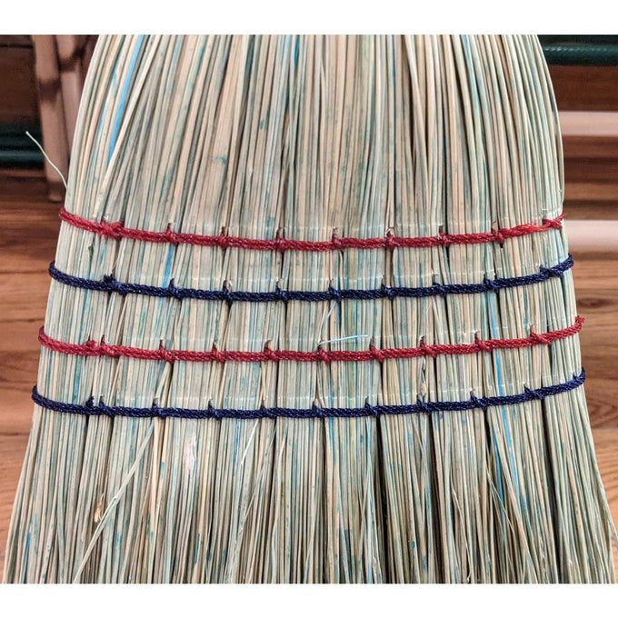 Close-up of handcrafted broom made with natural corn straw bound with alternating red and blue threads, showcasing quality Amish-made craftsmanship, ideal for household cleaning and home decor collections.
