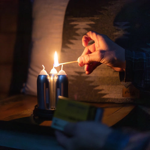 Handcrafted Candlelier Candle Lantern with three white candles being lit with a match indoors, offering warm light ideal for camping, emergency, farm, garden, and outdoor use.