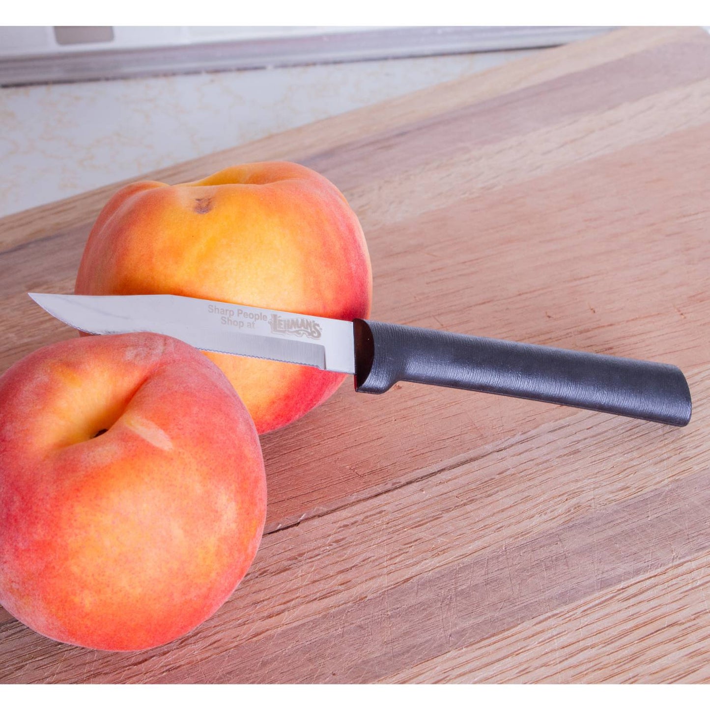Handcrafted serrated paring knife with fine high carbon stainless steel blade and smooth black handle, made in USA, shown with fresh peaches on wooden cutting board, ideal for kitchen food prep and Farm, Garden & Tool collections.
