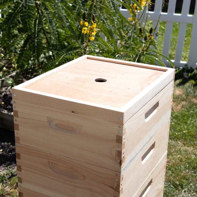Handcrafted Amish-made wooden bee escape board with a triangular maze design, crafted in the USA, set outdoors on grass near a white fence, ideal for chemical-free beekeeping.