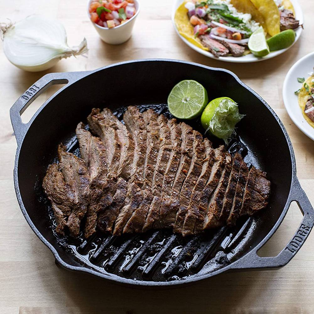 Handcrafted cast iron grill pan with dual handles cooking perfectly seared sliced steak garnished with halved lime, suitable for Kitchen & Food, Cookware, Cast Iron, and USA Made collections.