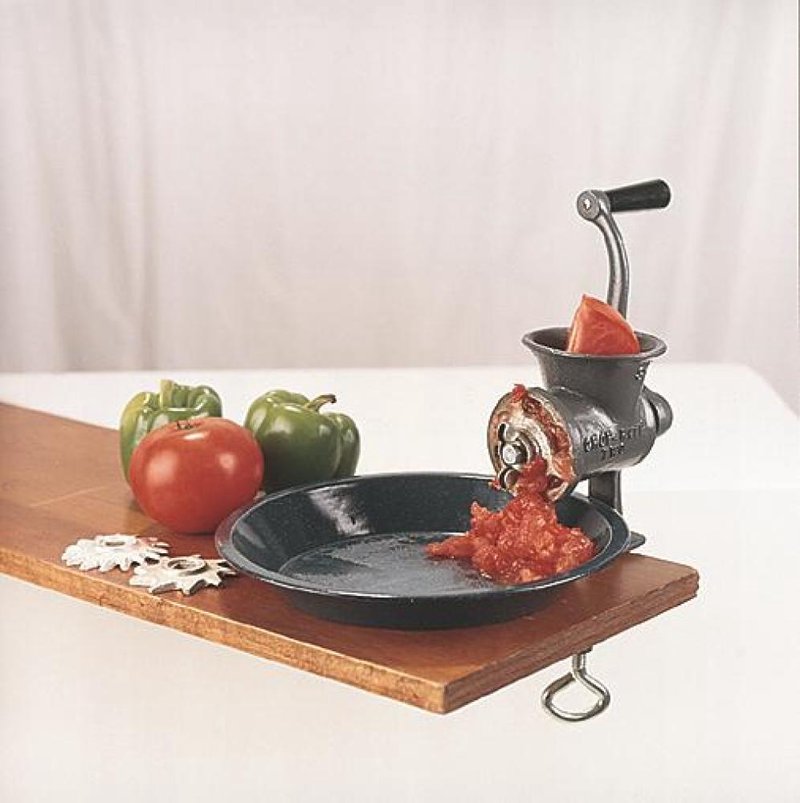Handcrafted food chopper with metal body and crank handle clamped to a wooden surface, grinding fresh tomatoes into sauce, ideal for Kitchen & Food, Specialty Equipment, Butchering Supplies, USA Made, and Best Sellers collections.
