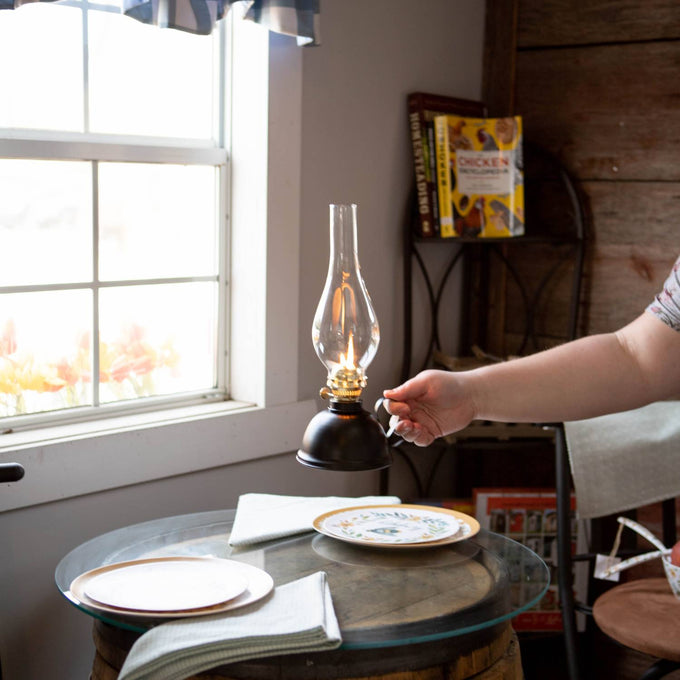 Handcrafted vintage-style Nomad oil lamp with a classic steel font and curved handle, emitting warm light, showcased in Farm, Garden & Tool and Emergency Supplies collections.