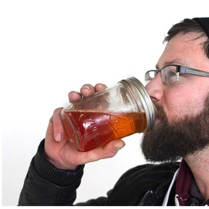 Man with glasses sipping iced tea from a wide-mouth mason jar fitted with a silver reusable drinking lid, part of Kitchen & Food, Dinnerware, Kitchen Gadgets, Kitchen Accessories, USA Made, Best Sellers, and Promo Eligible collections.