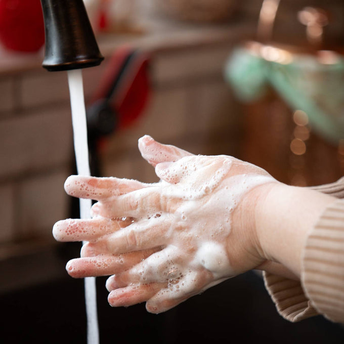 Person washing hands with foaming soap under running faucet, emphasizing gentle cleansing and moisturizing care, suitable for Health & Wellness and Grooming collections.