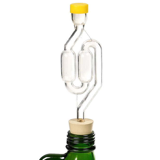 Clear glass S-shaped airlock with yellow cap and cork stopper set in a green bottle neck, designed for fermenting in kitchen, food preservation, and fermenting collections.
