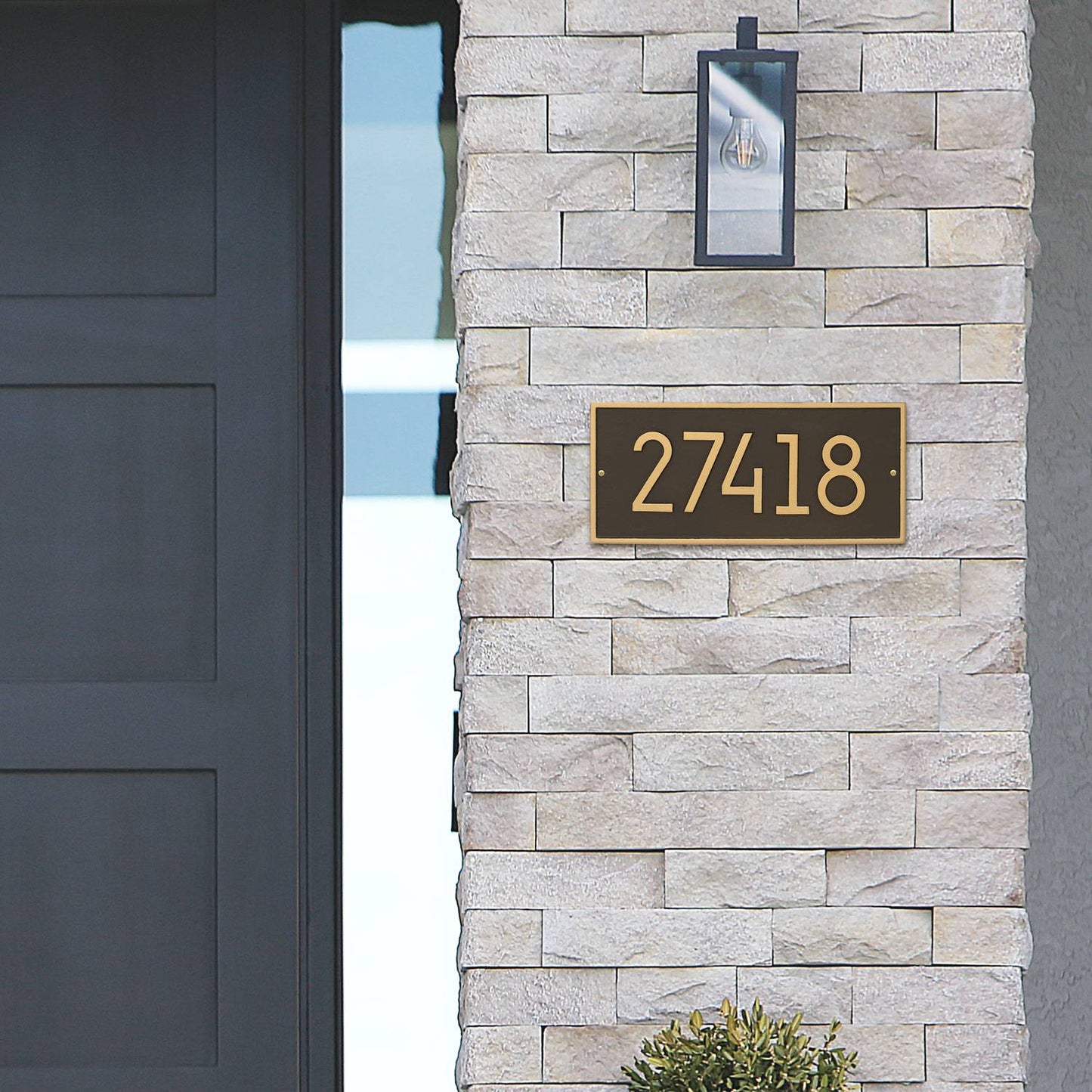 Modern custom wall plaque in aged bronze with gold-toned numbers mounted on light stone exterior, handcrafted in the USA, featured in Home & Decor and Mailboxes and Address Signs collections.