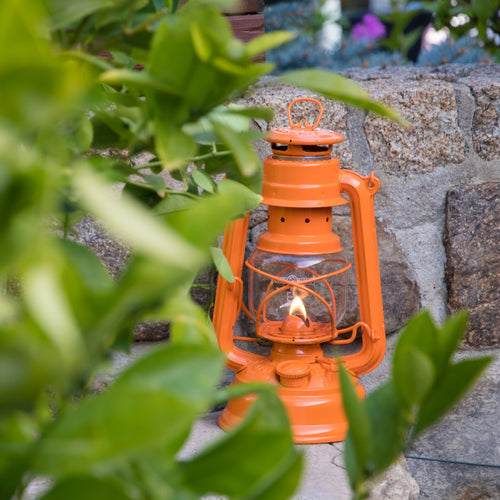 Handcrafted bright orange galvanized oil lantern with durable thermal heat-resistant globe lit outdoors on stone ledge, perfect for Camping, Emergency Supplies, and Lamps & Lighting collections.