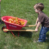 Young child pushing a handcrafted red wheelbarrow with sturdy wood handles and durable metal frame, filled with colorful autumn leaves, part of Toys, Books & Games and Lawn Games collections.