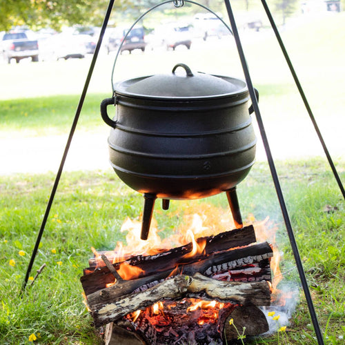 Handcrafted cast iron campfire kettle with round shape and three legs hanging over an open fire, designed for outdoor cooking in Farm, Garden & Tool, Camping, Best Sellers, and Promo Eligible collections.