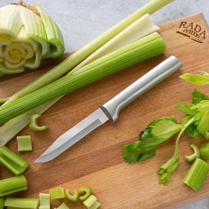 Handcrafted serrated paring knife with a finely toothed stainless steel blade and solid aluminum handle, made in USA, displayed on a wooden cutting board with fresh celery, ideal for Farm, Garden & Tool and Kitchen & Food collections.