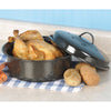 Black enamel-on-steel roaster with classic white speckles, cooked roast chicken inside, lid leaning nearby, surrounded by potatoes and carrots on blue checked cloth, Kitchen & Food cookware
