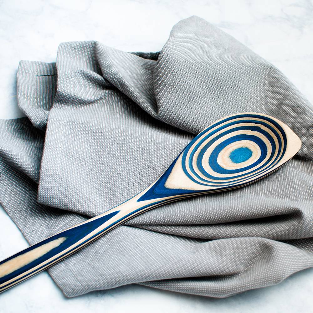 Handcrafted pakkawood corner spoon with bold concentric blue and natural wood patterns, resting on a textured gray cloth, featured in Kitchen & Food, Kitchen Gadgets, Cooking and Baking Helpers, Storage and Serving, Best Sellers, and Promo Eligible collections.