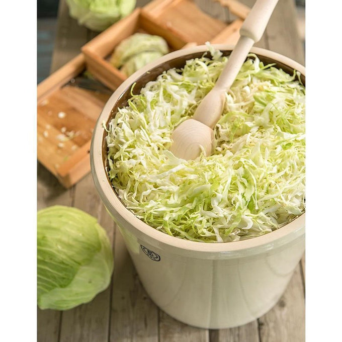 Handcrafted large stoneware crock filled with shredded cabbage and wooden tamper, used for fermenting and pickling, made in USA, ideal for Kitchen & Food and Food Preservation collections.