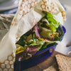 Set of three handmade wax-coated muslin wraps partially covering fresh salad in blue bowl, eco-friendly food storage solution from Kitchen & Food, Storage and Serving, USA Made collections.
