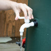 Close-up of a hand turning the white spigot of a green collapsible rain barrel, releasing flowing water; featured in Farm, Garden & Tool, Garden Accessories, Lawncare, Best Sellers, and Promo Eligible collections.