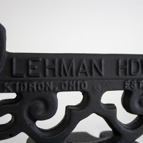 Close-up of a glossy black cast aluminum boot scraper featuring vintage scrollwork and embossed lettering, handcrafted in the USA, ideal for Home & Decor and Amish Made collections.