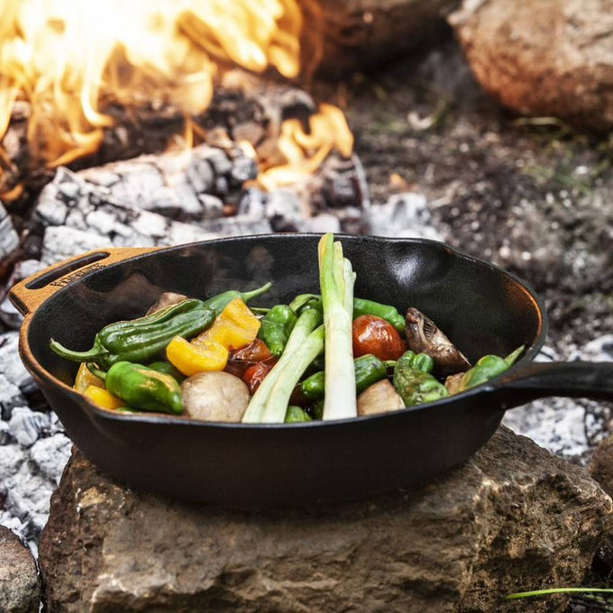 Cast iron skillet with a long handle cooking fresh vegetables over an open campfire, ideal for Farm, Garden & Tool, Camping, Kitchen & Food, Cookware, and Cast Iron collections.