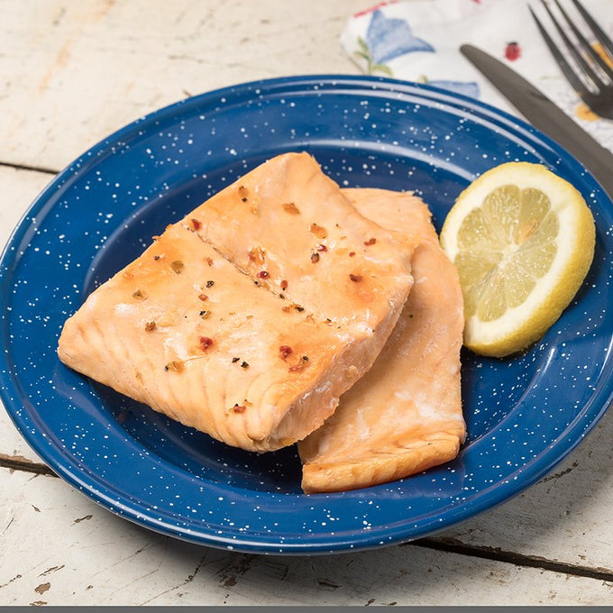 Two cooked salmon fillets seasoned with spices on a blue speckled plate, served with a lemon wedge, suitable for Kitchen & Food, Farm, Garden & Tool, Emergency Supplies, and Freeze Dried collections.