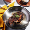 Handcrafted stainless steel fry pan with fully clad construction cooking a seared bone-in steak garnished with fresh herbs, featured in Kitchen & Food, Cookware, Pots and Pans collections.