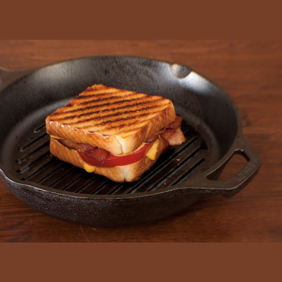 Handcrafted cast iron grill pan with raised ridges and assist handle, showing a grilled sandwich with melted cheese and tomato, ideal for Kitchen & Food, Cookware, Cast Iron, USA Made, Best Sellers, Promo Eligible collections.