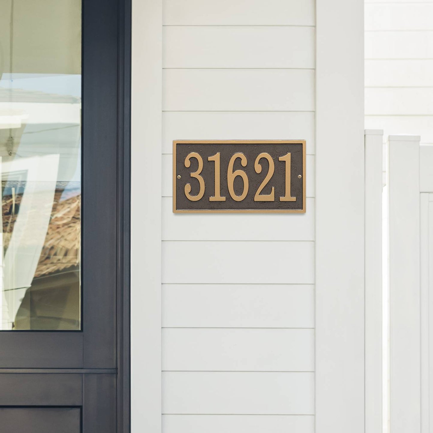Bronze and gold rectangular custom address plaque mounted on white siding next to a black-framed glass door, handcrafted in USA, suitable for Home & Decor and Mailboxes and Address Signs collections.