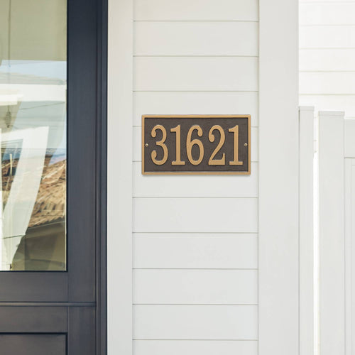 Bronze and gold rectangular custom address plaque mounted on white siding next to a black-framed glass door, handcrafted in USA, suitable for Home & Decor and Mailboxes and Address Signs collections.