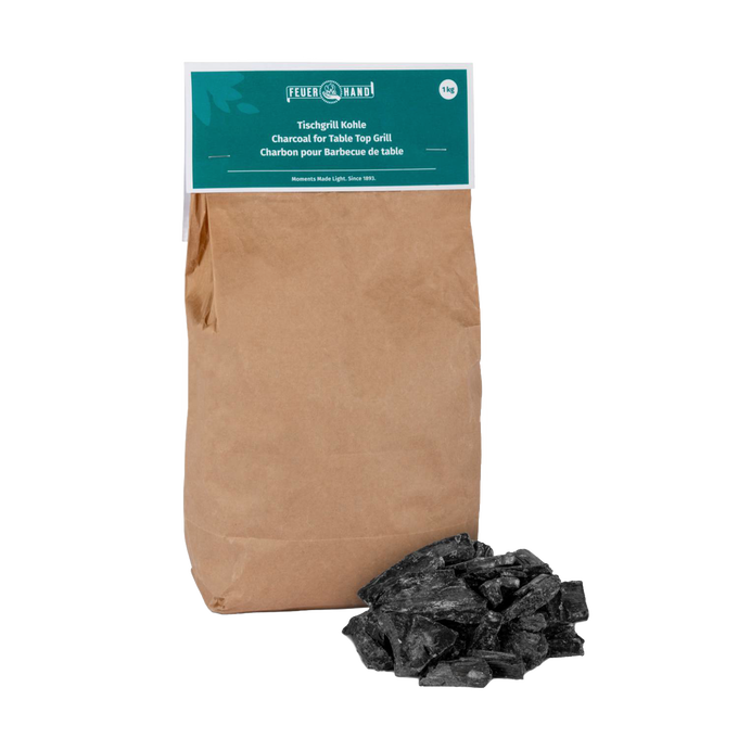 Brown paper bag of Feuerhand charcoal for tabletop grills with a small pile of black charcoal pieces, suitable for grilling in Stoves, Grilling, and Best Sellers collections.