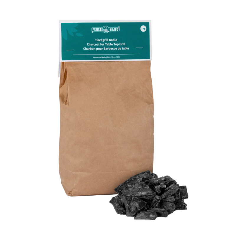 Brown paper bag of Feuerhand charcoal for tabletop grills with a small pile of black charcoal pieces, suitable for grilling in Stoves, Grilling, and Best Sellers collections.
