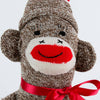 Hand-sewn vintage-inspired sock monkey toy made in USA from classic red and white heel socks, featuring a cheerful knitted face and red ribbon bow, perfect for indoor play and children's toys.