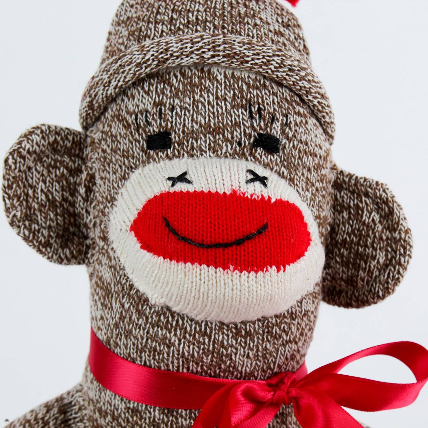 Hand-sewn vintage-inspired sock monkey toy made in USA from classic red and white heel socks, featuring a cheerful knitted face and red ribbon bow, perfect for indoor play and children's toys.