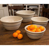 Set of four handcrafted stoneware mixing bowls with blue stripes, arranged on a wooden table with fresh oranges, ideal for Kitchen & Food and Baking Supplies collections.