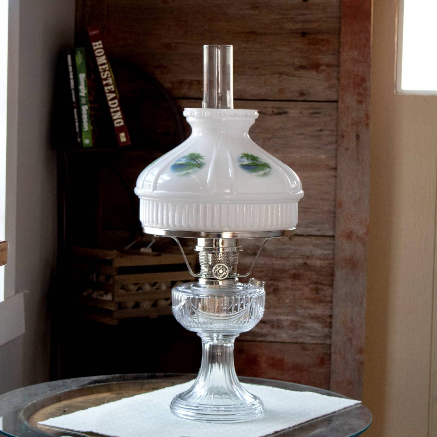 Classic oil lamp with clear glass base and white glass shade featuring painted tropical beach scenes; fits standard 10-inch shade rings, perfect for lamps and lighting collections.
