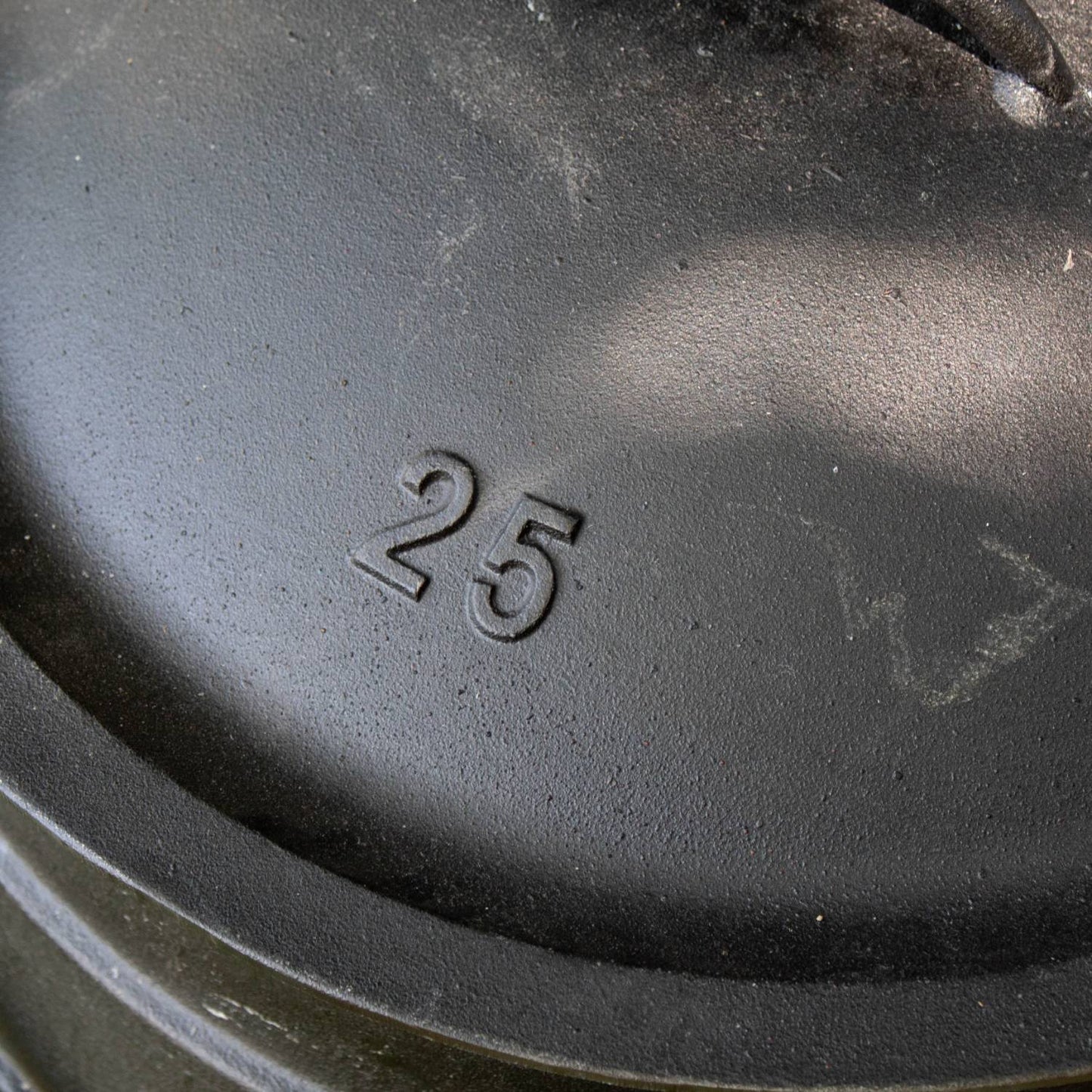 Close-up of the cast iron campfire kettle lid embossed with the number 25, highlighting durable construction for outdoor use in Farm, Garden & Tool, Camping, Best Sellers, and Promo Eligible collections.