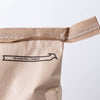 Close-up of a sealed brown paper bag with a stitched pull thread and printed arrow indicating how to open, suitable for pantry, food storage, and emergency supplies collections.